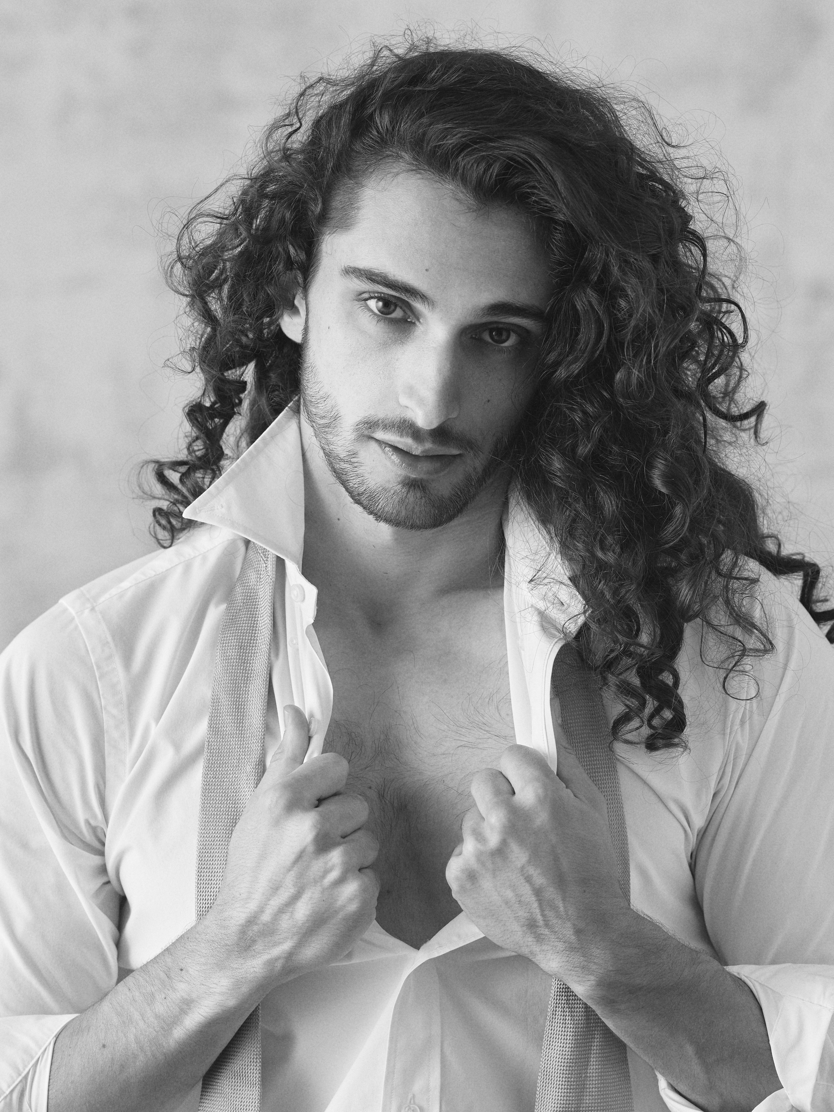 Unbuttoned white shirt with golden tie medium shot in black and white.